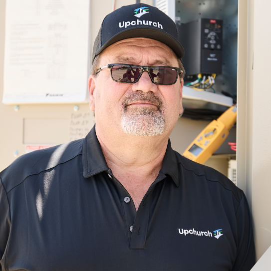 Upchurch employee wearing a hat and sunglasses in the field