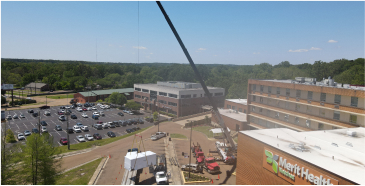 Merit Health rooftop air unit installation on top of a hospital building with a crane